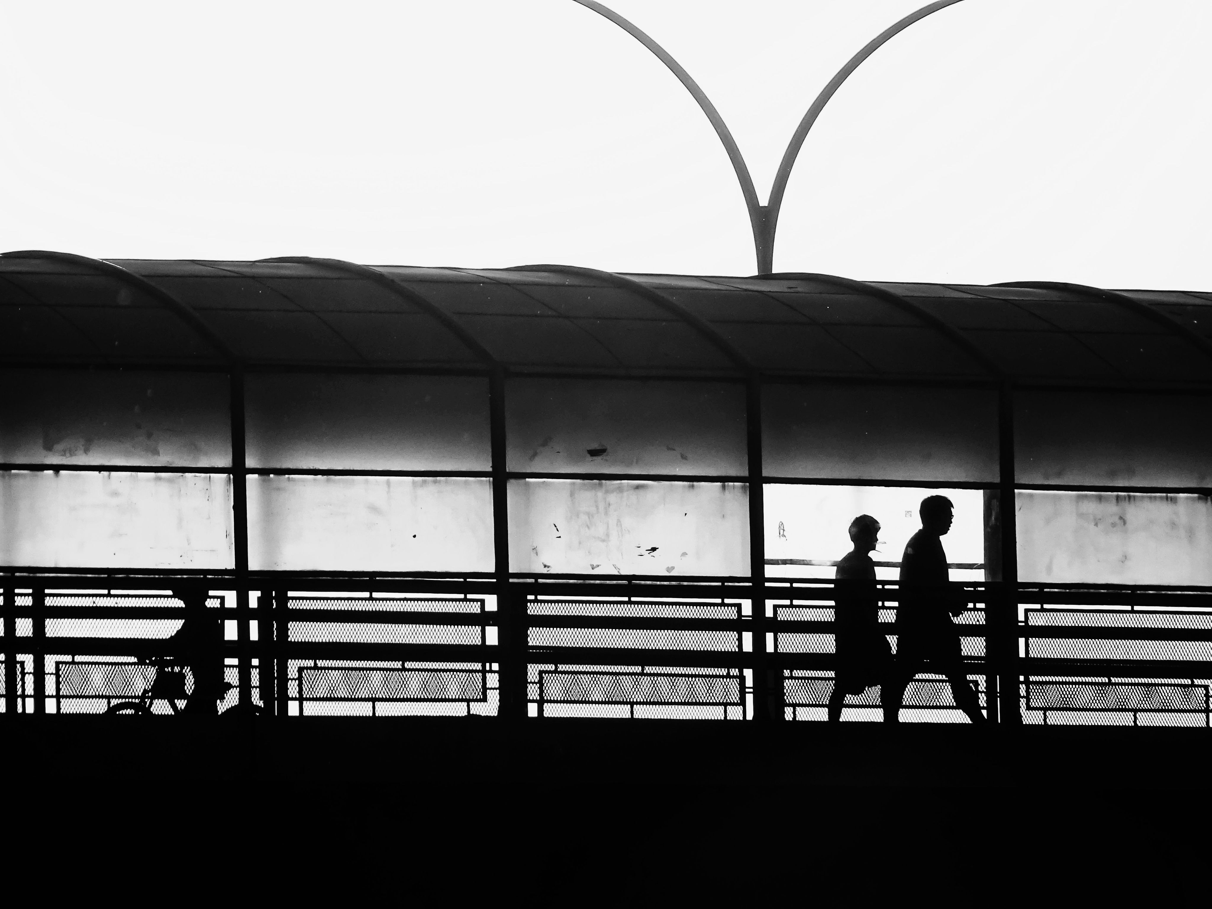 Two silhouetted figures walking together through a modern covered walkway